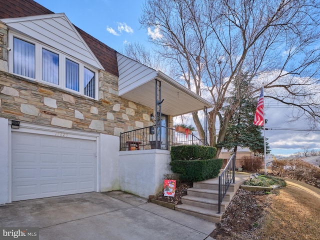 view of side of property featuring stone siding, driveway, and an attached garage