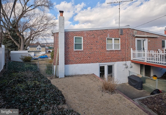 rear view of property with brick siding, a chimney, and fence private yard