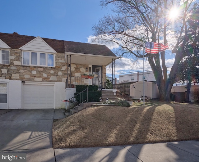 view of front of house featuring driveway, a garage, stone siding, stairway, and a shed