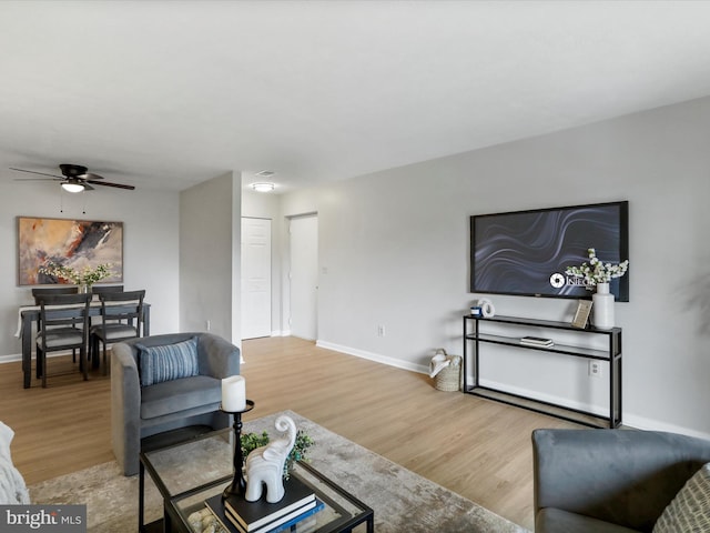 living area featuring ceiling fan, baseboards, and wood finished floors