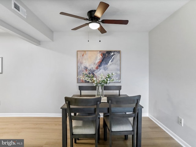 dining room featuring baseboards, visible vents, ceiling fan, and wood finished floors