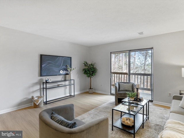 living room featuring visible vents, light wood-style flooring, and baseboards