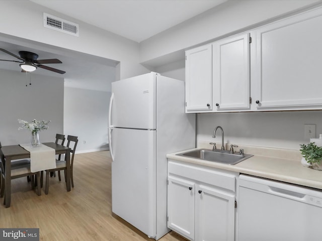 kitchen with white appliances, white cabinets, and a sink