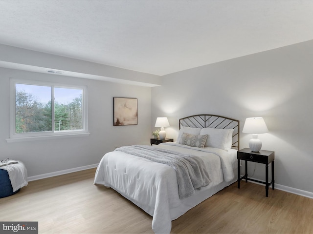 bedroom featuring light wood-style flooring, visible vents, and baseboards