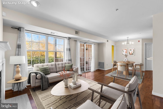 living room featuring dark wood finished floors, visible vents, a fireplace, and baseboards