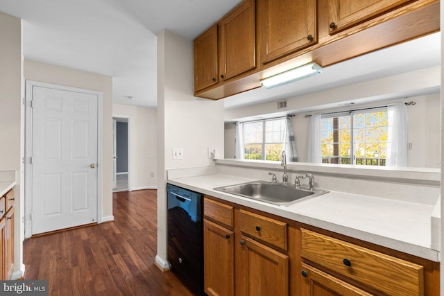 kitchen featuring light countertops, brown cabinetry, dark wood-type flooring, a sink, and dishwasher