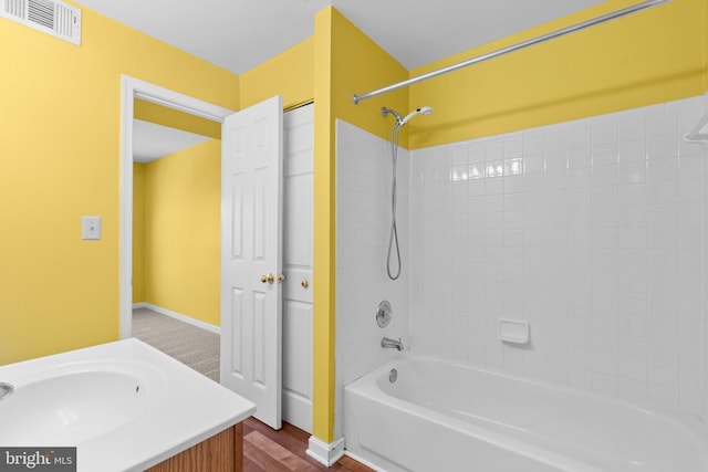 bathroom with baseboards, washtub / shower combination, visible vents, and vanity