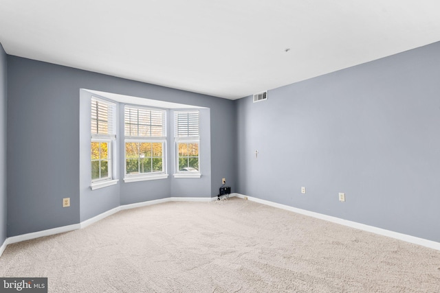 spare room with carpet floors, visible vents, and baseboards