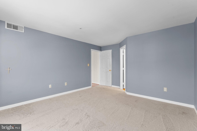 carpeted spare room featuring visible vents and baseboards