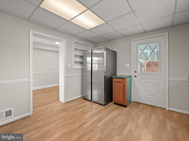 kitchen featuring a paneled ceiling, light wood-type flooring, freestanding refrigerator, visible vents, and brown cabinetry