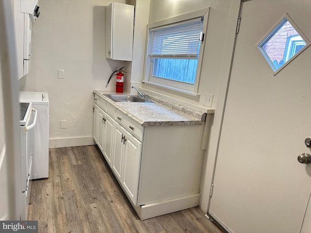 kitchen with plenty of natural light, white cabinets, light countertops, light wood-style floors, and a sink