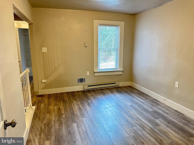 unfurnished room with a baseboard radiator, visible vents, baseboards, and wood finished floors