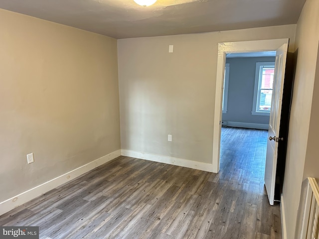 spare room with a baseboard heating unit, radiator heating unit, baseboards, and wood finished floors