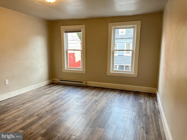 unfurnished room featuring baseboards, a baseboard heating unit, and wood finished floors