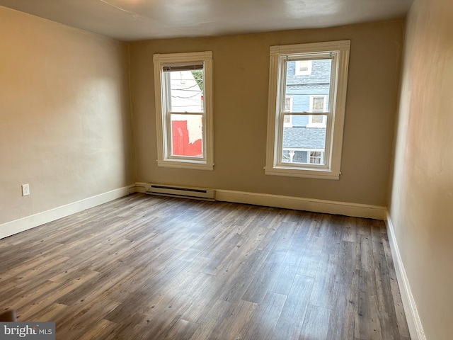 spare room featuring baseboards, baseboard heating, and wood finished floors