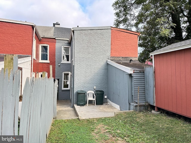 rear view of house featuring a patio area, brick siding, a lawn, and fence