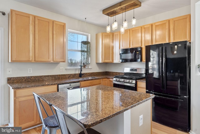 kitchen featuring dark stone counters, a kitchen breakfast bar, a center island, black appliances, and a sink