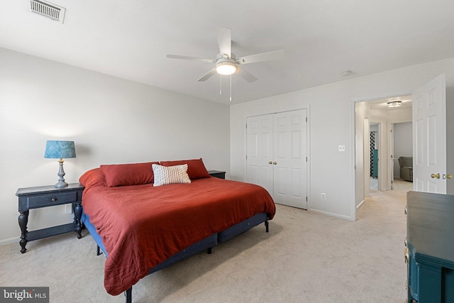 bedroom with a closet, light colored carpet, visible vents, ceiling fan, and baseboards