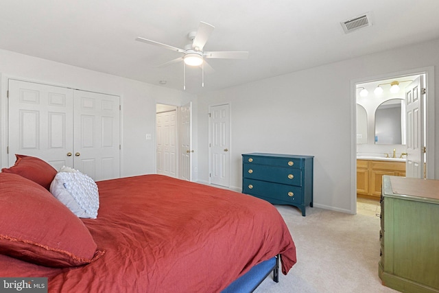 bedroom featuring arched walkways, two closets, visible vents, ensuite bathroom, and light carpet