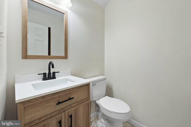 bathroom featuring baseboards, vanity, and toilet