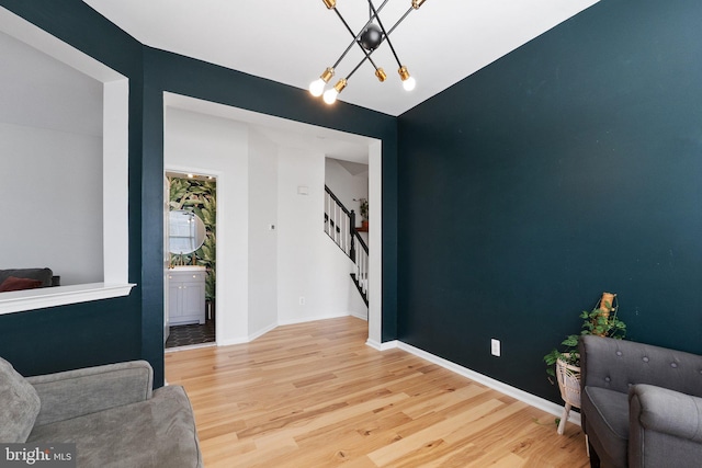 living area with stairs, a notable chandelier, wood finished floors, and baseboards