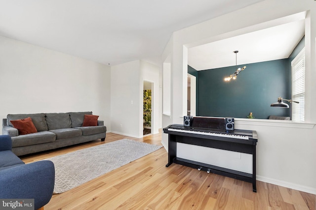 living room with a notable chandelier, baseboards, and wood finished floors