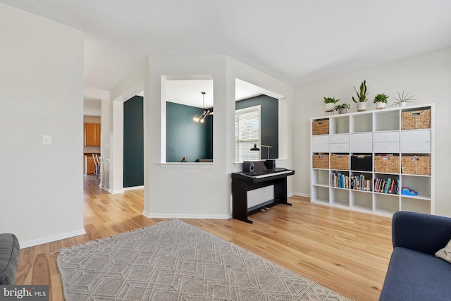 living area with baseboards, an inviting chandelier, and wood finished floors