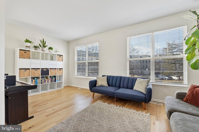 living area featuring visible vents, baseboards, and wood finished floors