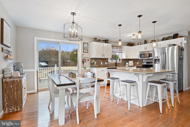 dining room with a chandelier, light wood-style flooring, and baseboards