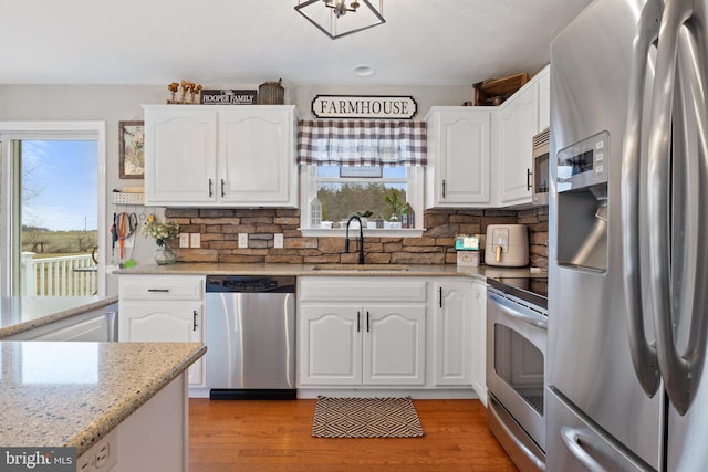 kitchen featuring appliances with stainless steel finishes, light wood-type flooring, white cabinetry, and a sink