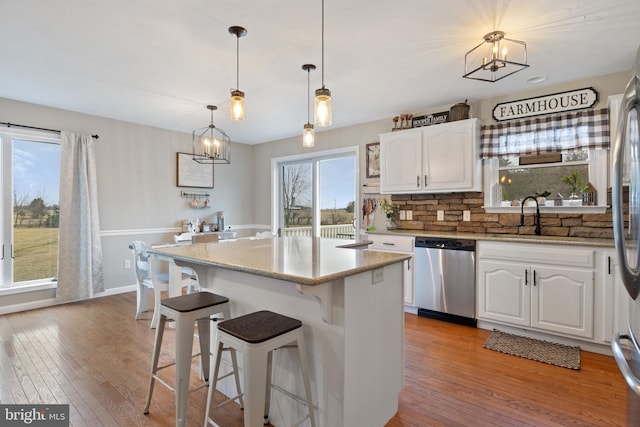 kitchen featuring light wood-style flooring, a kitchen island, white cabinetry, and stainless steel dishwasher