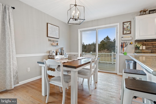 dining area with an inviting chandelier, light wood-style flooring, and baseboards