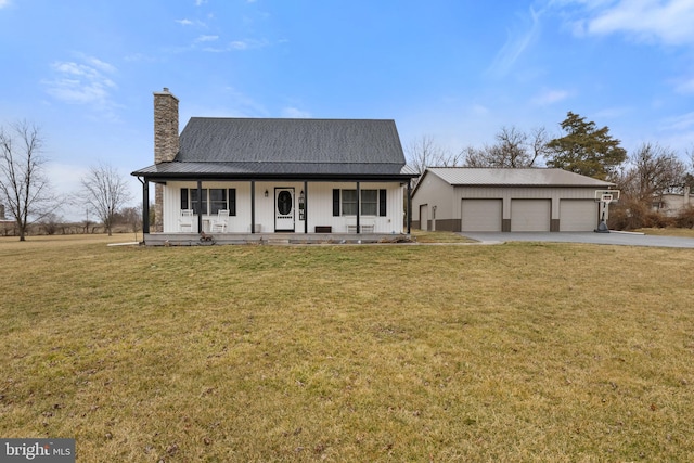 view of front facade with a chimney, covered porch, a front yard, metal roof, and a garage