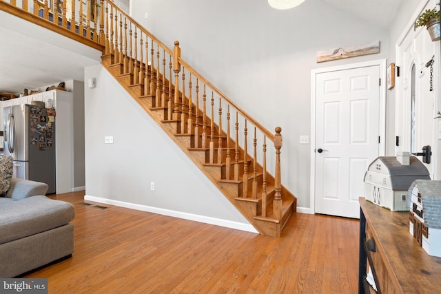 foyer with baseboards, visible vents, light wood finished floors, and stairs