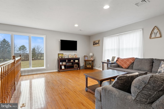 living room with a healthy amount of sunlight, visible vents, baseboards, and light wood finished floors