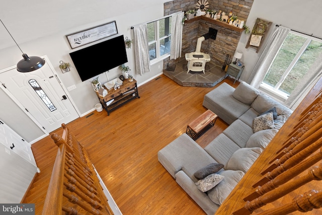 living room featuring a wood stove, visible vents, baseboards, and wood finished floors