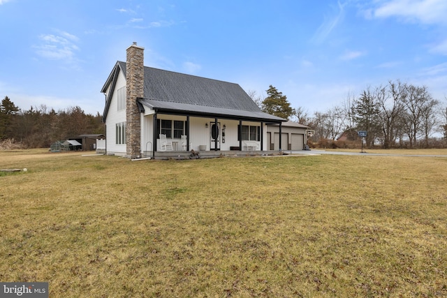 view of front of home with covered porch, a chimney, an attached garage, and a front yard