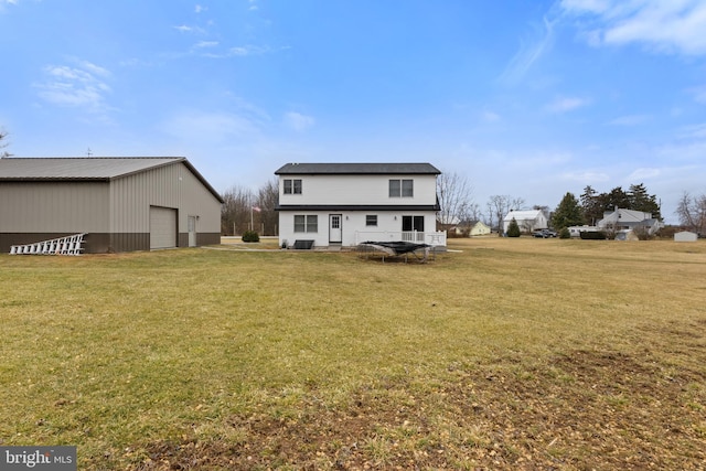 rear view of property with a lawn, a detached garage, and an outdoor structure