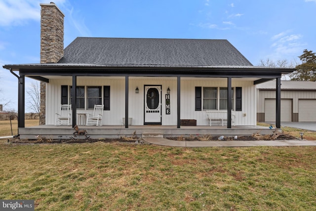 view of front of property featuring covered porch, a garage, an outdoor structure, a chimney, and a front yard