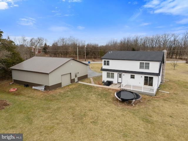 rear view of property with a garage, an outdoor structure, driveway, a lawn, and a pole building