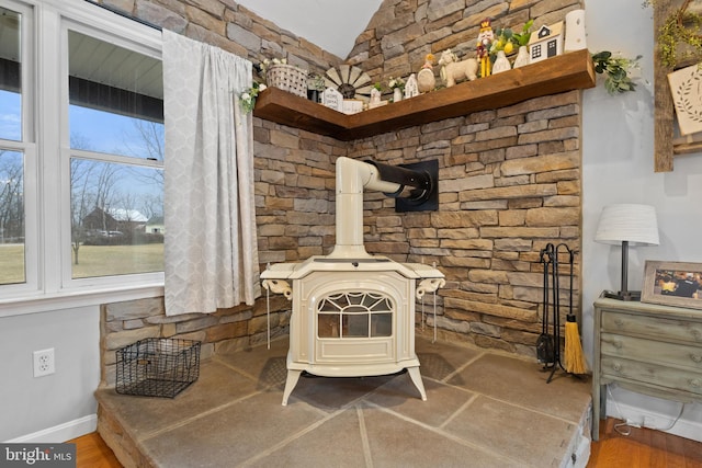 room details with a wood stove, baseboards, and wood finished floors