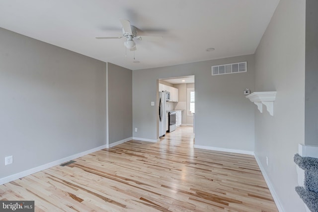 unfurnished room featuring light wood finished floors, visible vents, ceiling fan, and baseboards