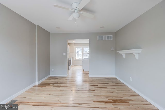 unfurnished room with a ceiling fan, light wood-style floors, visible vents, and baseboards