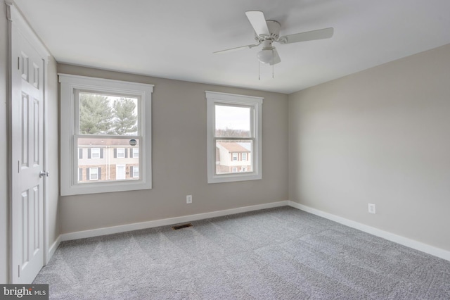 carpeted empty room featuring visible vents, baseboards, and a ceiling fan