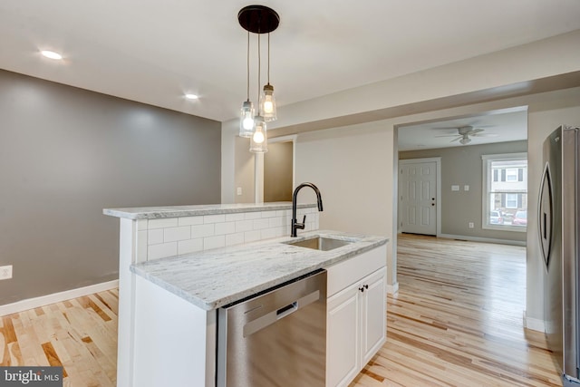 kitchen with light wood-style flooring, light stone counters, appliances with stainless steel finishes, and a sink