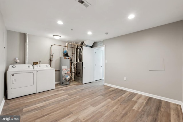 laundry room featuring laundry area, visible vents, washer and clothes dryer, light wood-style flooring, and water heater