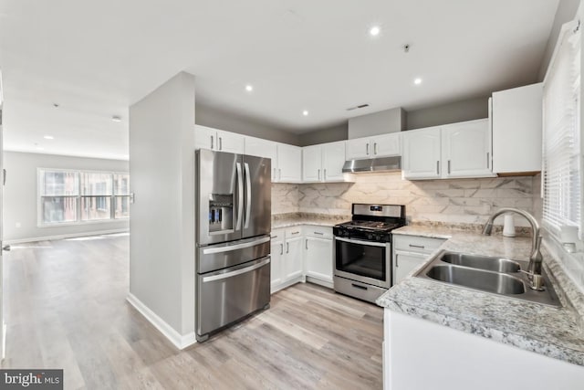 kitchen featuring stainless steel appliances, a sink, light wood-style flooring, and under cabinet range hood