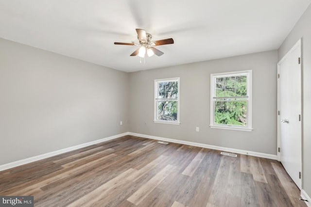 unfurnished room featuring visible vents, ceiling fan, baseboards, and wood finished floors