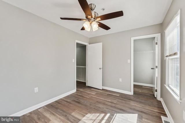 unfurnished bedroom featuring a closet, multiple windows, wood finished floors, and baseboards