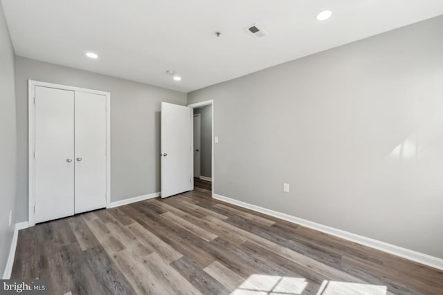 unfurnished bedroom featuring recessed lighting, a closet, visible vents, wood finished floors, and baseboards